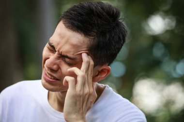 Baş ağrısı olan Asyalı genç bir adam. 