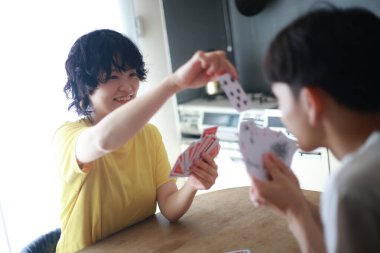 Mutlu Asyalı çift evde kağıt oynuyor.