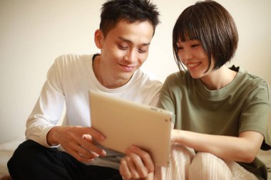 Genç Asyalı çift tablet bilgisayar kullanıyor.