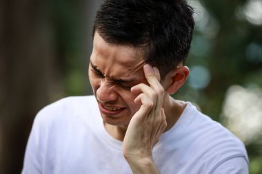 Baş ağrısı olan Asyalı genç bir adam. 