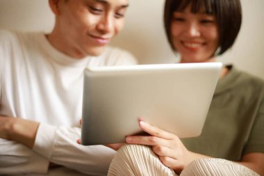 Genç Asyalı çift tablet bilgisayar kullanıyor.