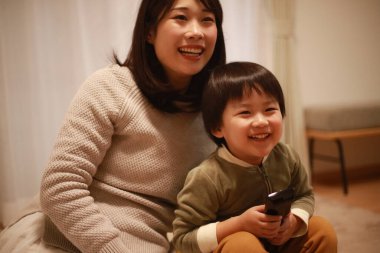 Asyalı genç kadın ve uzaktan kumandalı küçük oğlu. 