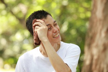 Stresli Asyalı adam terini havluyla temizliyor.