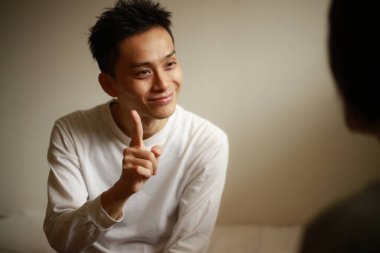 Yakışıklı Asyalı adam el kol hareketi yapıyor.