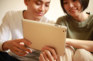 Genç Asyalı çift tablet bilgisayar kullanıyor.