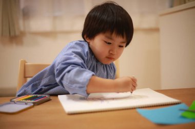 Evde çizim yapan şirin bir çocuk.