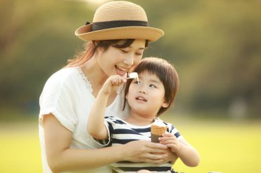 Anne, küçük oğlu için parkta dondurma besler.