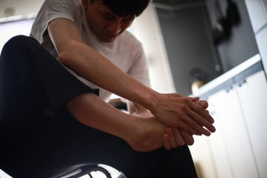 Asyalı adam evinde bacak ağrısı çekiyor.