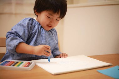 Evde çizim yapan şirin bir çocuk.