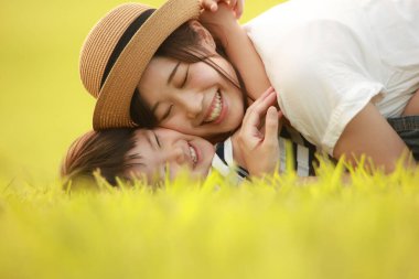 Mutlu anne ve oğul çimenlerde oynuyorlar.