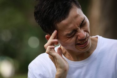 Baş ağrısı olan Asyalı genç bir adam. 