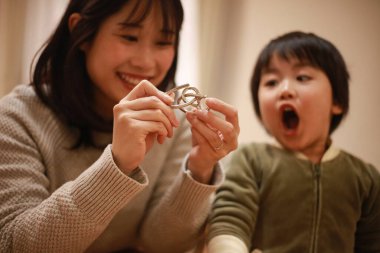 Asyalı genç kadın ve küçük oğlu oynuyorlar. 