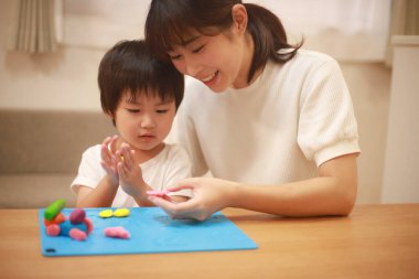 Anne ve oğlu çamurla oynuyor.