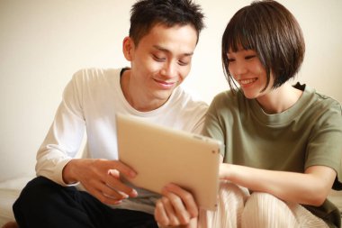 Genç Asyalı çift tablet bilgisayar kullanıyor.