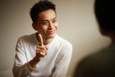 Yakışıklı Asyalı adam el kol hareketi yapıyor.