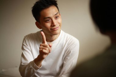 Yakışıklı Asyalı adam el kol hareketi yapıyor.