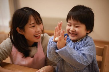 Küçük çocuk ve annesi mangırla oynuyorlar. 