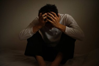 Elleri başının üstünde üzgün genç bir adam. 