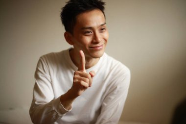 Yakışıklı Asyalı adam el kol hareketi yapıyor.