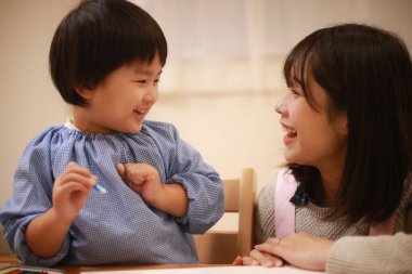 Annesiyle birlikte çizen yakışıklı Asyalı çocuk.
