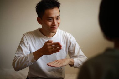 Yakışıklı Asyalı adam el kol hareketi yapıyor.