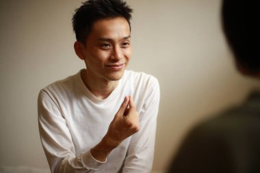 Yakışıklı Asyalı adam el kol hareketi yapıyor.