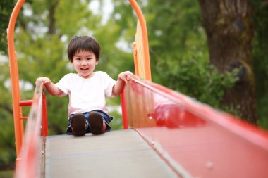 Asyalı çocuk oyun alanında kayıyor