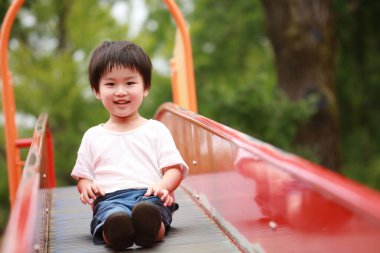 Asyalı çocuk oyun alanında kayıyor