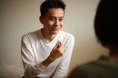 Yakışıklı Asyalı adam el kol hareketi yapıyor.