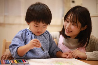 Annesiyle birlikte çizen yakışıklı Asyalı çocuk.