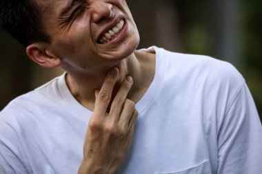 Boğazı ağrıyan Asyalı bir adamın yakın çekimi. 