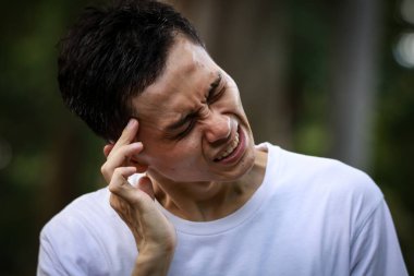 Baş ağrısı olan Asyalı genç bir adam. 