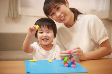 Anne ve oğlu çamurla oynuyor.