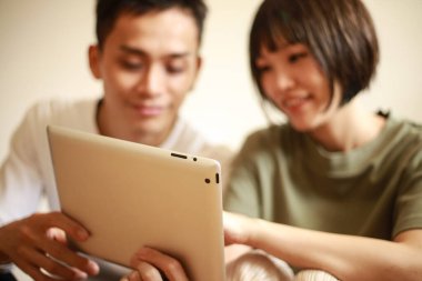 Genç Asyalı çift tablet bilgisayar kullanıyor.