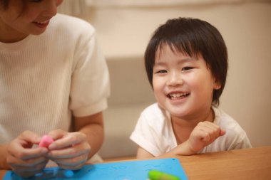 Anne ve oğlu çamurla oynuyor.