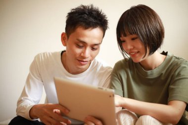 Genç Asyalı çift tablet bilgisayar kullanıyor.