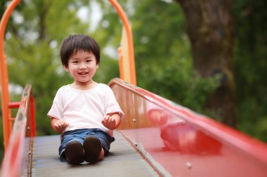 Asyalı çocuk oyun alanında kayıyor