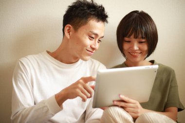 Genç Asyalı çift tablet bilgisayar kullanıyor.