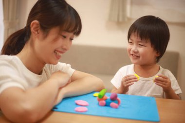 Anne ve oğlu çamurla oynuyor.