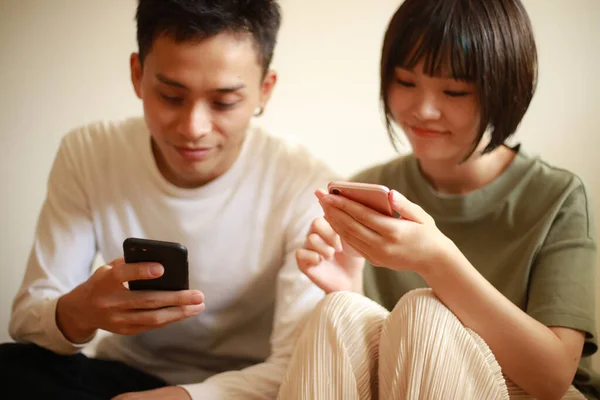 Pareja Asiática Usando Teléfonos Móviles Mientras Está Sentado Sofá Casa — Foto de Stock