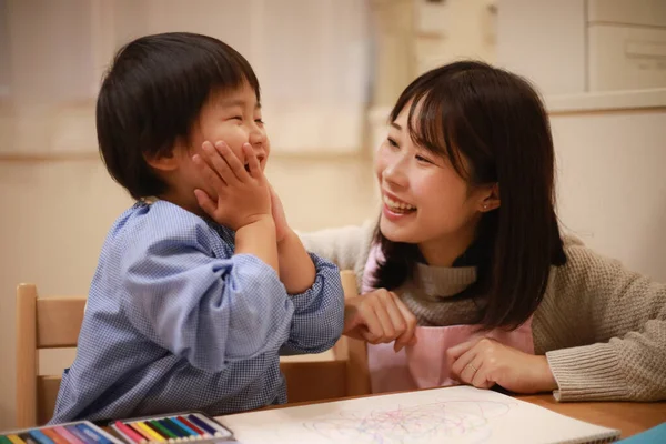 Annesiyle birlikte çizen yakışıklı Asyalı çocuk.