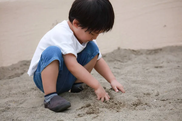 Küçük çocuk kum ile kumsalda oynarken.