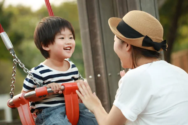 公園の遊び場で一緒に遊んでいる若い母親と愛らしい幸せな小さな息子 — ストック写真