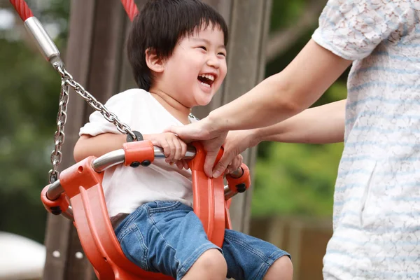 Asyalı anne ve oğlu oyun bahçesinde.