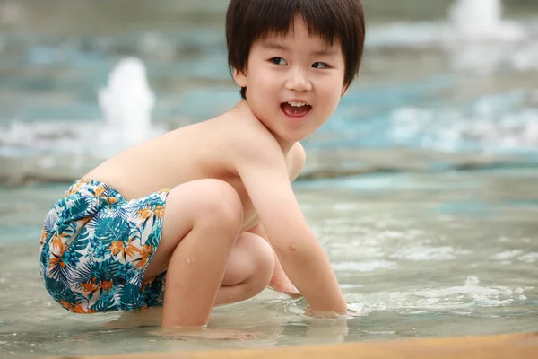 アジアのかわいい男の子が噴水で遊んでいます — ストック写真