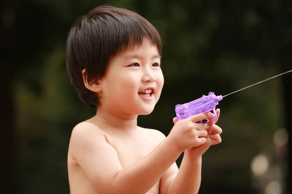アジア系の少年が水鉄砲で遊んでいます — ストック写真