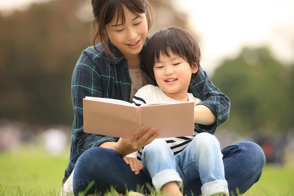 Azjatycki Matka Czytanie Książki Dla Jej Syn Letni Park — Zdjęcie stockowe