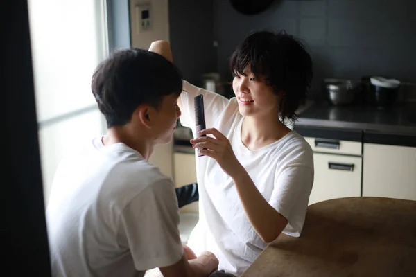 若いアジア人の女性が家で彼氏の髪を切って — ストック写真