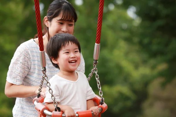 Asyalı anne ve oğlu oyun bahçesinde.