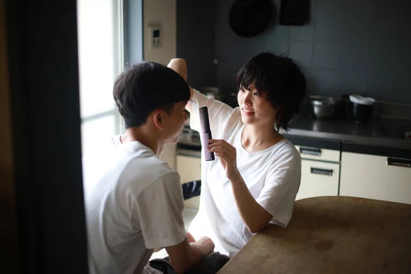 Молодая Азиатская Женщина Стрижет Волосы Своего Парня Дома — стоковое фото